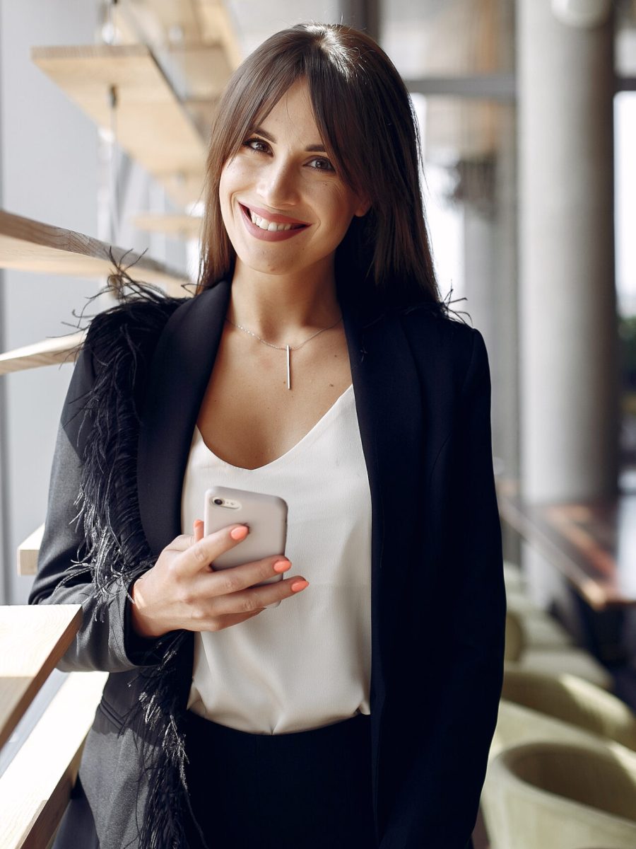 Beautiful woman working. Busineswoman in a stylish clothes. Woman standing near window with phone